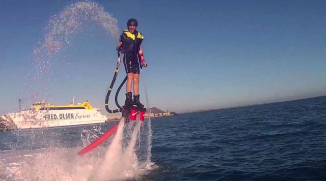 hombre feliz en el agua con un barco de fondo